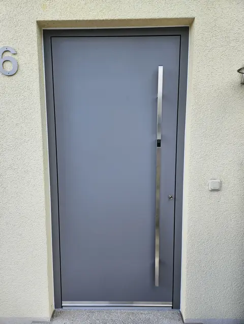 Graue Haustür mit durchgehendem Edelstahlgriff